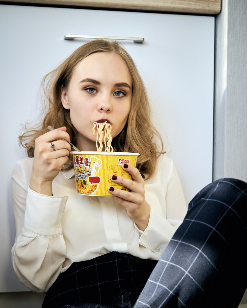 20-something woman eating a bowl of ramen.